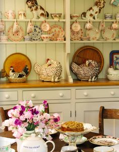 a dining room table with plates and bowls on top of it next to a china cabinet