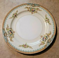 a white plate with flowers on it sitting on top of a tile floor next to a wall