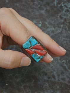 This fantastic ring displays deep red Mediterranean coral inlays flanked by natural, handshaped turquoise inlays. The components are inlayed, yet rise above the surface. The shank of the ring is heavily cast silver. c. 1950s Size: 13 Height: 1" Weight: 22g Artisan Red Jewelry With Inlay, Artisan Red Inlay Jewelry, Red Inlay Ring, Red Inlay Ring Jewelry, Red Ring With Inlay, Red Sterling Silver Ring With Inlay, Red Sterling Silver Rings With Inlay, Unique Red Multi-stone Turquoise Ring, Traditional Turquoise Inlay Ring