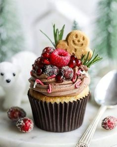 a cupcake decorated with raspberries, chocolate frosting and sprinkles