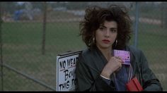 a woman sitting on top of a bench holding a cell phone in her hand and looking at the camera