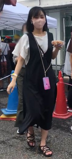 a woman wearing a face mask and holding a slice of pizza in her hand while walking down the street