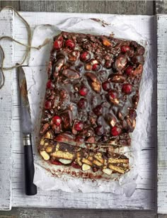 a square piece of chocolate with nuts and cranberries next to a pair of scissors