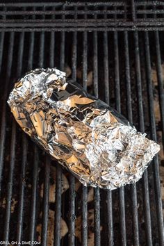 a piece of foil wrapped in aluminum foil on top of a bbq grill with charcoal