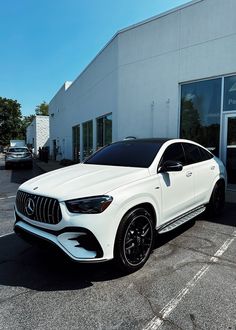 a white mercedes gle is parked in front of a building with black rims