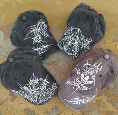 four hats with white ink on them sitting on the ground next to each other,