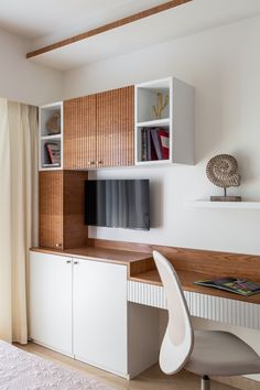 a room with a desk, bookshelf and television on it's wall