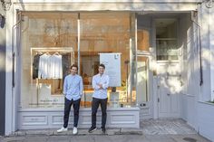 two men standing in front of a clothing store