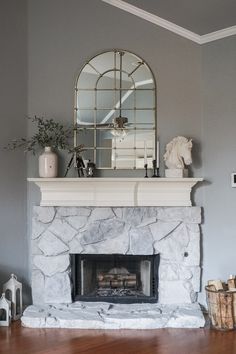 a living room with a fireplace and mirror on the wall above it's mantle