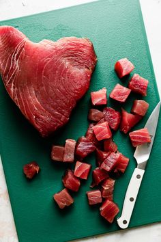 raw meat and diced vegetables on a green cutting board with a knife next to it