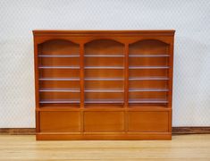 a wooden bookcase sitting on top of a hard wood floor next to a wall