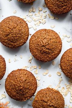 several muffins on a white surface with oats scattered around them, top view