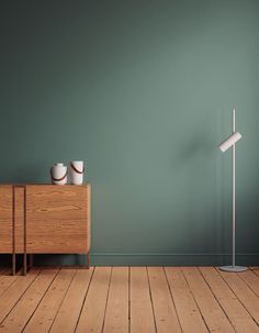 an empty room with green walls and two white bowls on a wooden table next to a lamp