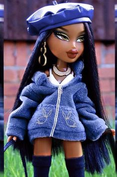 a doll with long black hair wearing a blue jacket and hat, standing in the grass