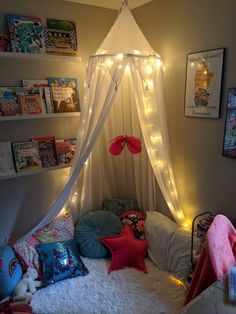 a canopy bed with lights on the ceiling and pillows under it in a child's bedroom