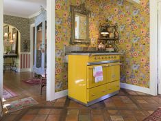 a yellow stove sitting in the middle of a living room next to a wall with flowers on it