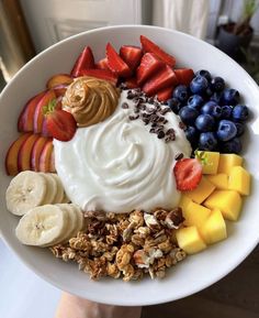 a white plate topped with fruit and yogurt next to sliced bananas, strawberries