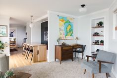 a living room filled with furniture and a painting on the wall above a wooden table