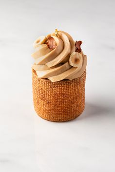 a cupcake with banana slices and nuts on top is sitting on a white surface