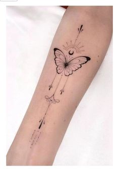 a small butterfly tattoo on the arm with arrows and stars coming out of its wings