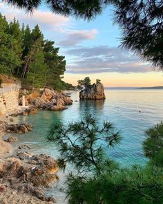 the beach is surrounded by trees and rocks