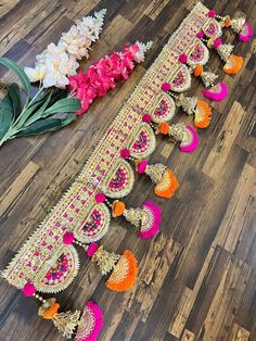 an elaborately decorated table runner with flowers and garlands on the floor next to it