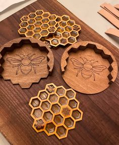 three wooden coasters with bees and honeycombs carved into them on a table