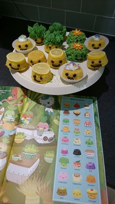 cupcakes are arranged on top of a table with an open book next to them