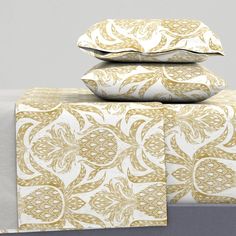 three pillows are stacked on top of each other in front of a white and gold wall