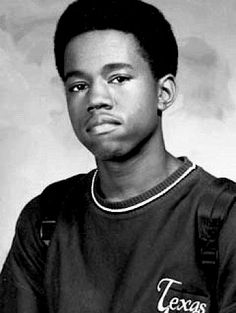 a young man in a maroon shirt is posing for a photo with his hand on his hip