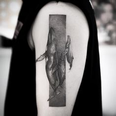 a black and white photo of two dolphins on the back of a woman's shoulder