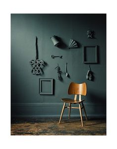 a wooden chair sitting in front of a wall with pictures on it and hanging from the ceiling