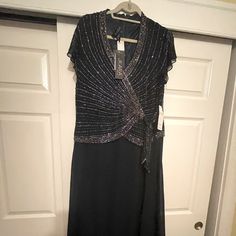 a black dress with silver sequins is hanging on a white door and there is a hanger in front of it