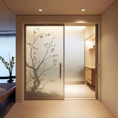 a room with a glass door that has a tree on it and flowers in the vase