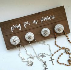 a wooden sign that says pray for us sinns with rosary beads and cross on it