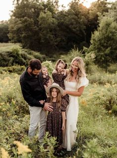 a family posing for a photo in the middle of a field with tall grass and trees