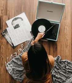 a woman sitting on the floor next to an open record player