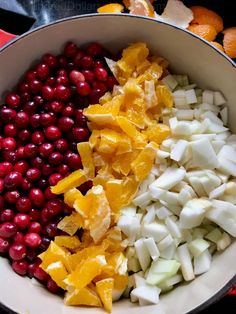 a bowl filled with cranberries, oranges and other food items on top of a table