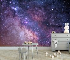 a space themed wallpaper in a child's room with a table and chair