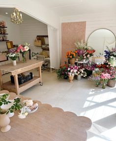 a room filled with lots of different types of flowers and vases on the tables