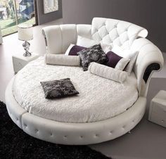 a white round bed with lots of pillows on it