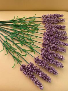 lavender flowers are arranged on a white surface with green stems and purple leaves in the center