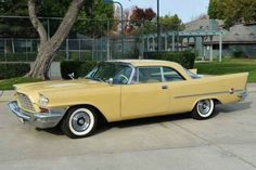 an old yellow car parked in a parking lot