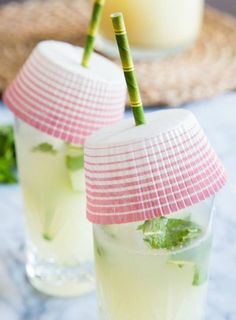 two glasses filled with drinks sitting on top of a table next to a straw hat