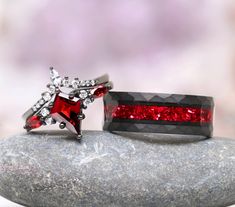 two red and white rings sitting on top of a rock next to each other,