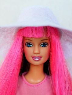 a barbie doll with pink hair wearing a white hat and blue eyes is looking at the camera