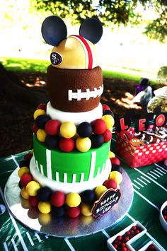 a football themed cake on a table with other desserts in the background and decorations around it