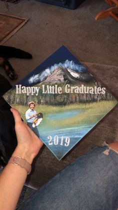 a person holding up a graduation cap with the words happy little graduates on it