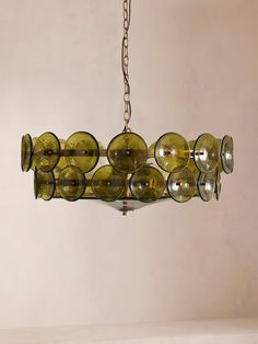 a chandelier hanging from a chain with green glass circles on it's sides