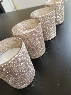 four glittered candles are sitting on a table with one lit candle in the middle